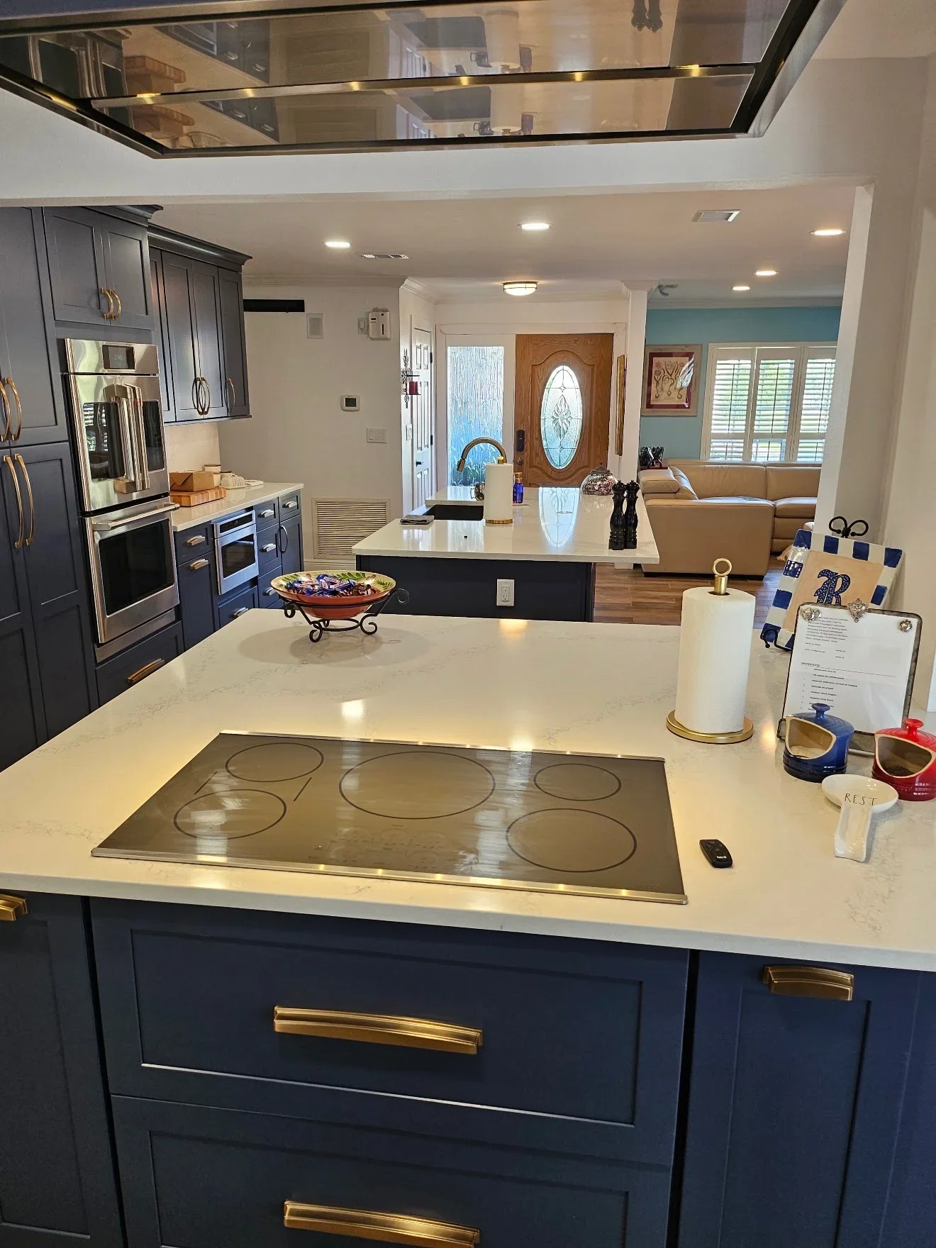 Navy kitchen cabinets with brass pulls, white quartz island countertop, and integrated electric cooktop