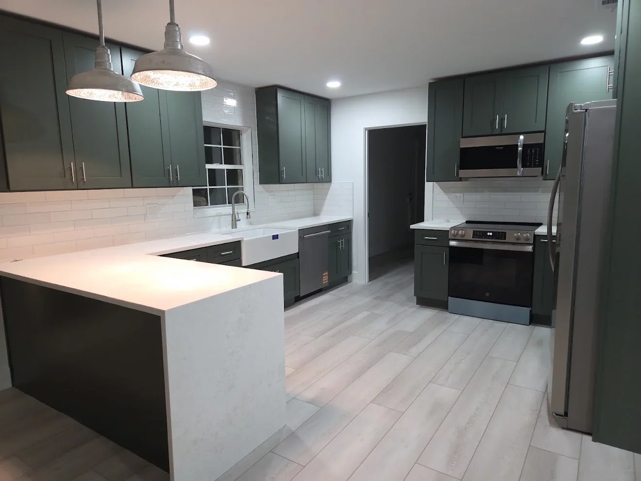 Kitchen with sage green cabinets, white quartz counters, stainless steel appliances, and plank flooring