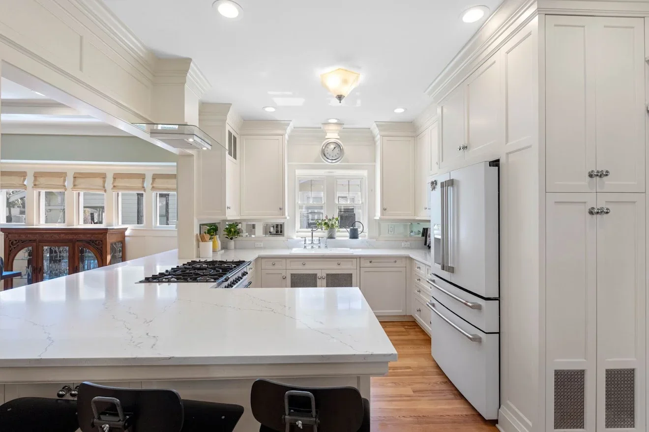 White kitchen with quartz countertops, custom cabinetry, gas cooktop, and stainless steel appliances