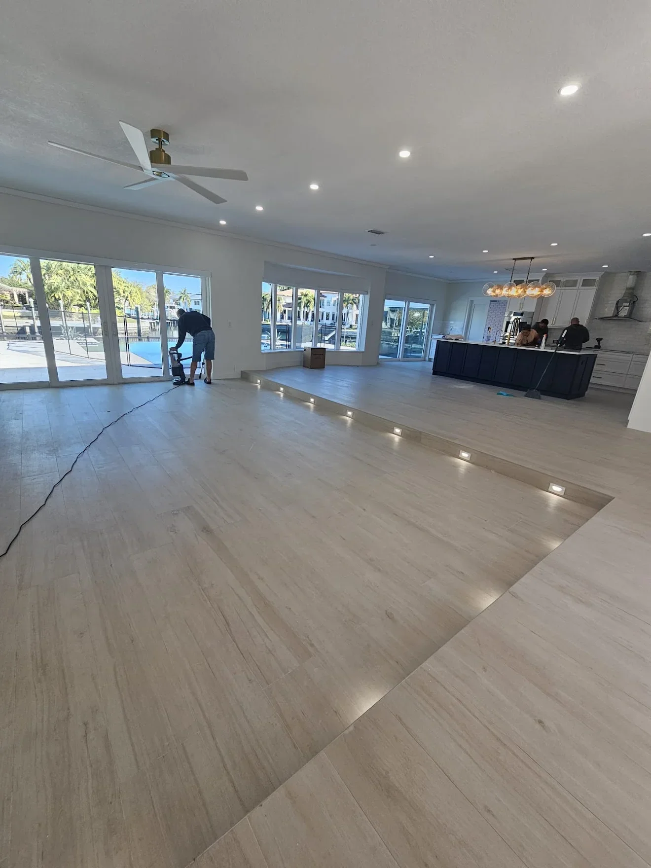 Open commercial space with light wood flooring, recessed lighting, and modern kitchen cabinetry