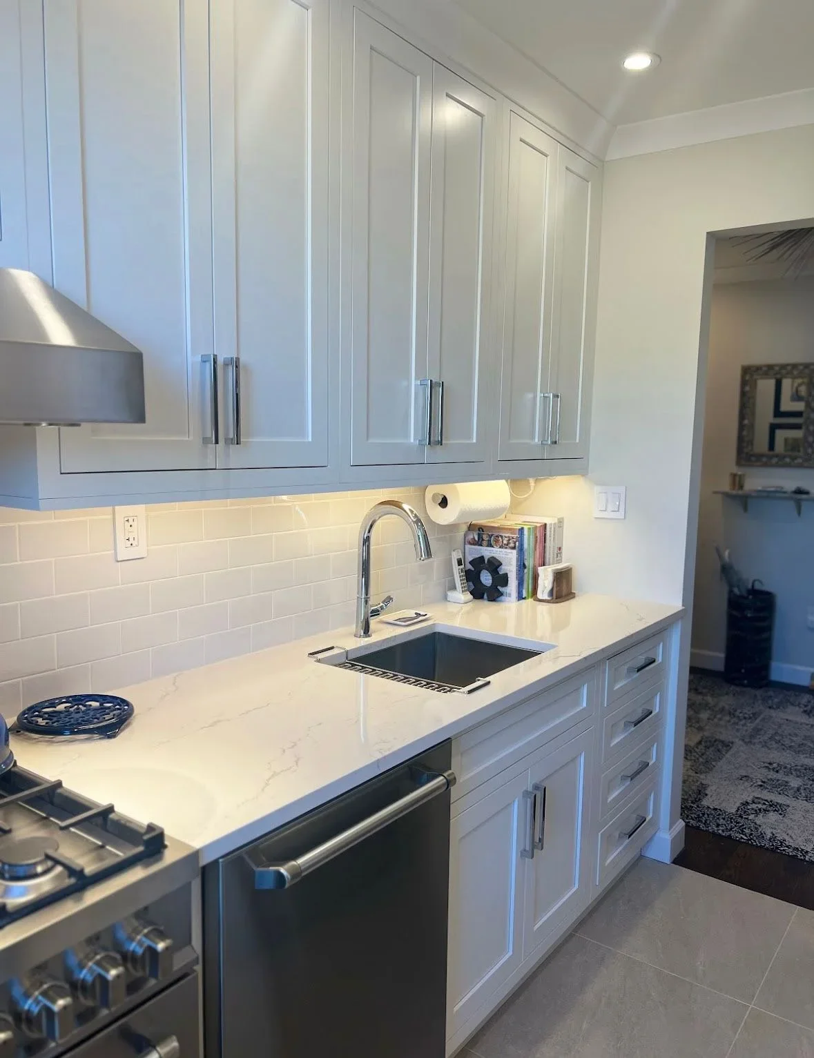 White kitchen with glass-front cabinets, subway tile backsplash, quartz counters, and stainless steel appliances