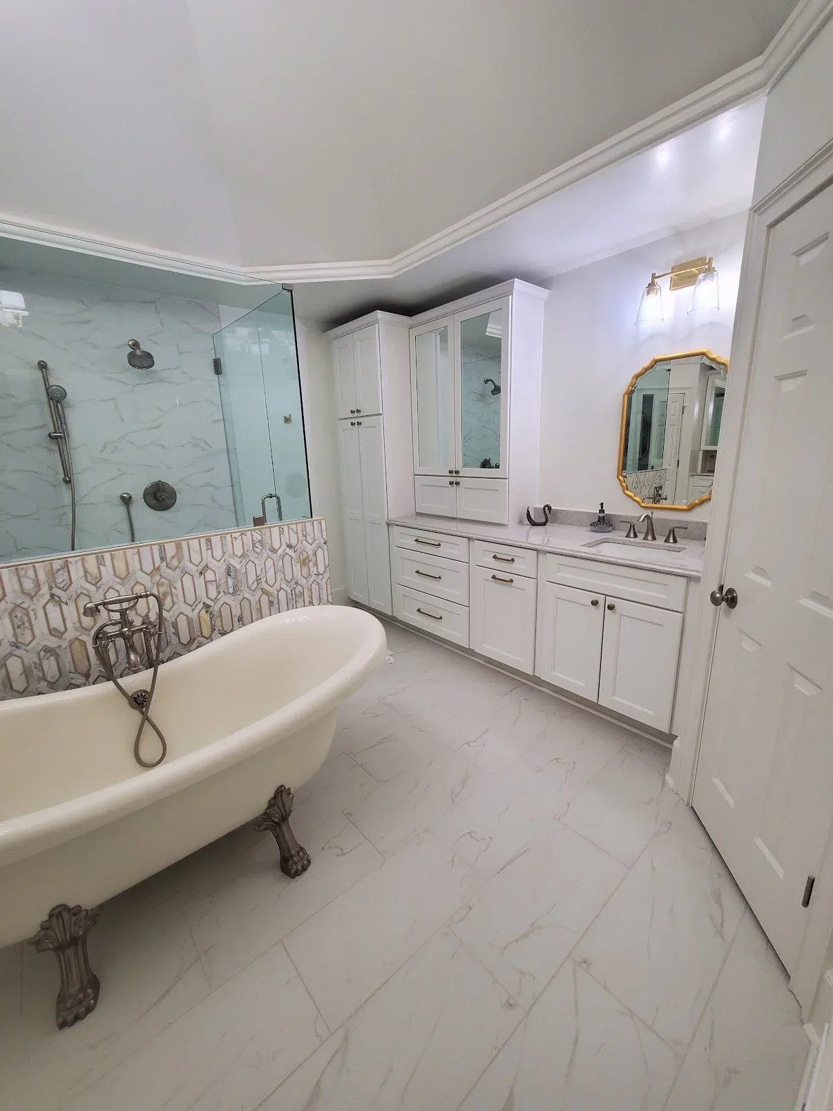 Master bathroom with marble flooring, white cabinetry, freestanding tub, and glass shower enclosure