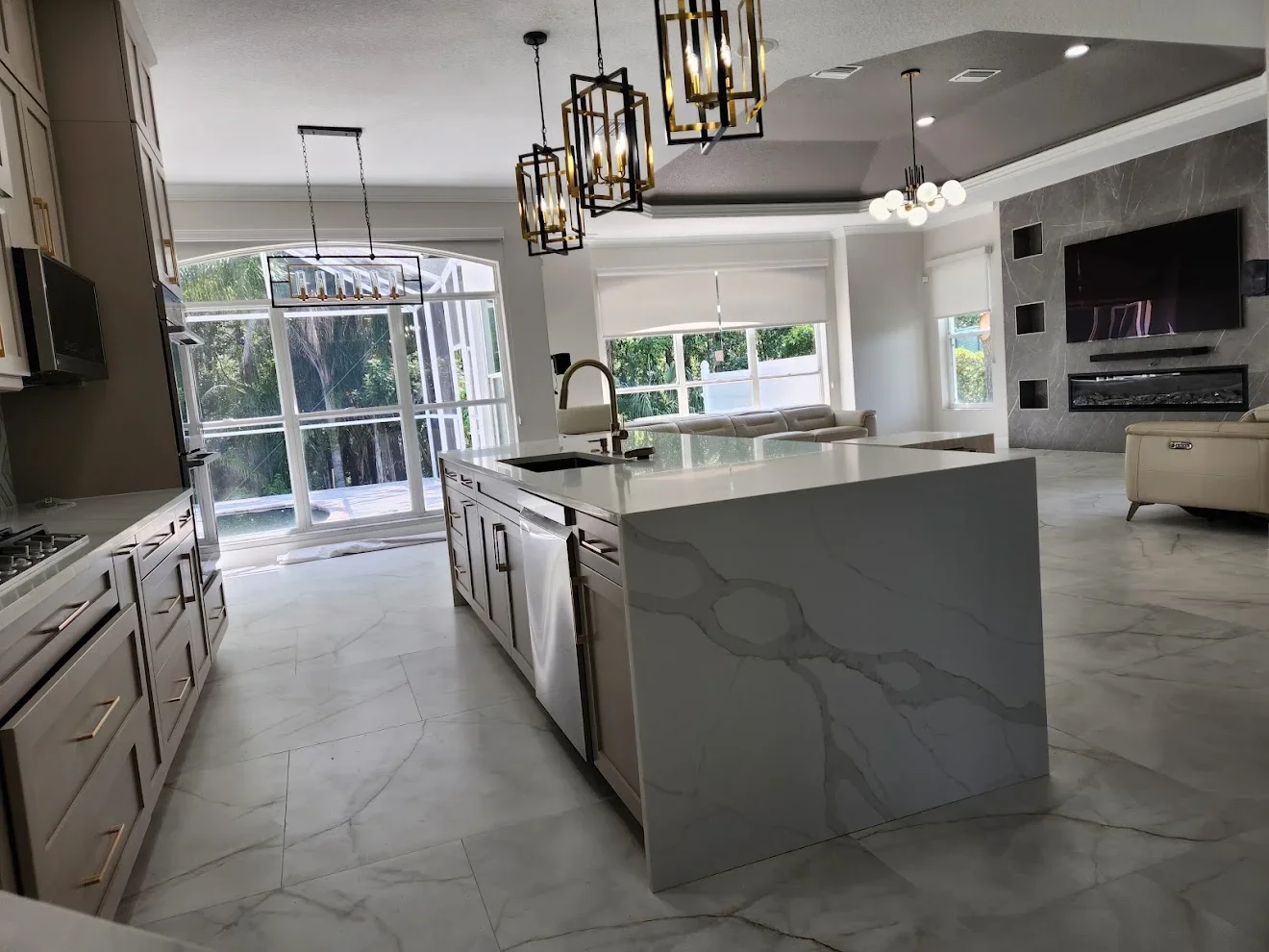 Modern kitchen with marble flooring, white cabinetry, quartz island, and stainless steel appliances